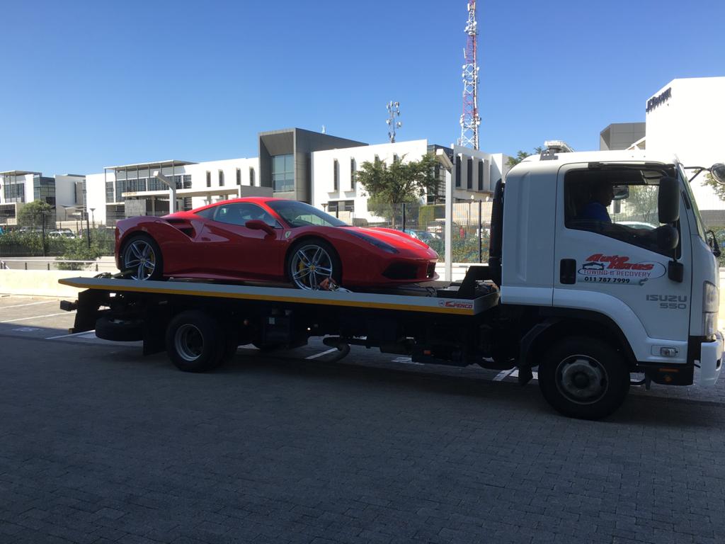 Autohaus flatbed tow truck carrying a red sports car